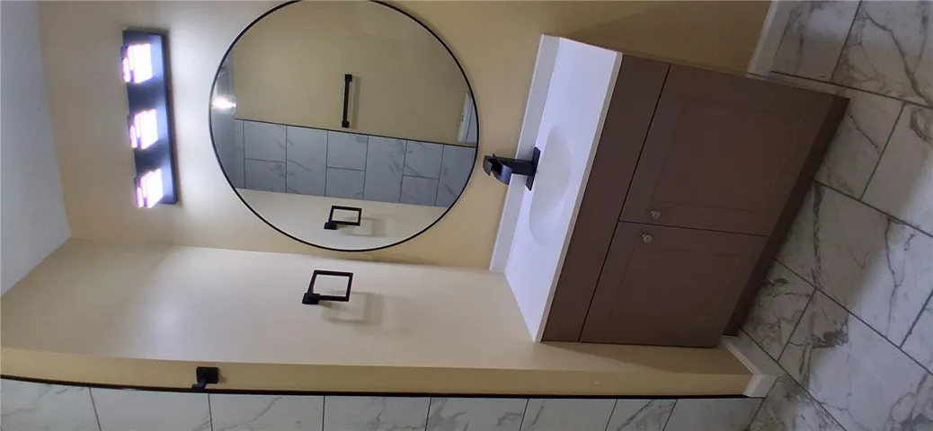 This modern bathroom features a stylish vanity and a sleek circular mirror.