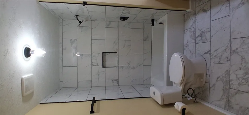 This newly renovated bathroom features a clean design with modern fixtures and a spacious shower.