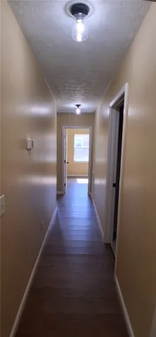 This interior hallway features durable flooring and leads to bedrooms.