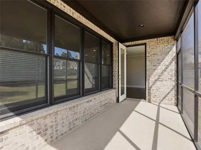 A well-lit screened porch offers a tranquil extension of indoor living with views of the surrounding green space.