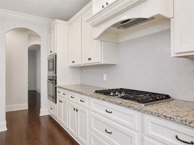 White cabinetry with granite counters and rich hardwood flooring defines this functional kitchen.