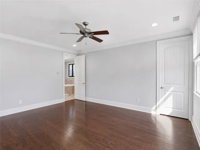 Rich hardwood floors complement the neutral tones in this spacious sleeping chamber.