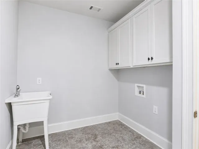 Ample cabinetry and a utility sink create a highly functional laundry space.