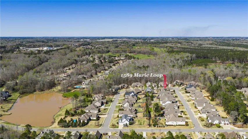 An aerial perspective reveals a vibrant neighborhood nestled among lush woodlands and a tranquil pond.