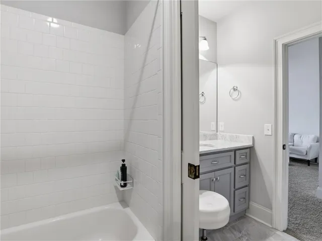 A pristine bathroom featuring a tiled tub and a vanity with ample storage.