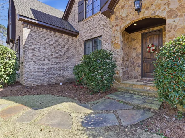 A welcoming stone entryway with a solid wood door and mature landscaping enhances the home's impressive curb appeal.