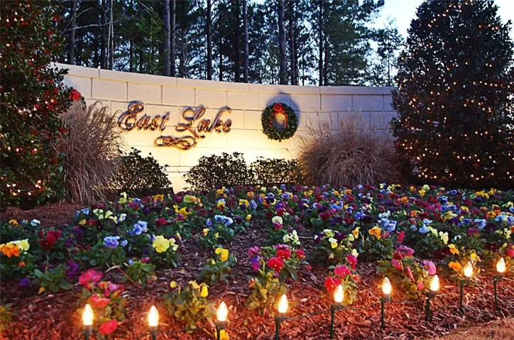 Welcoming entry to East Lake with a vibrant flower bed and charming accent lighting.