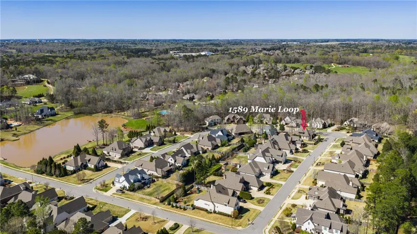 An aerial panorama showcases a peaceful neighborhood with private lake and verdant woodlands.