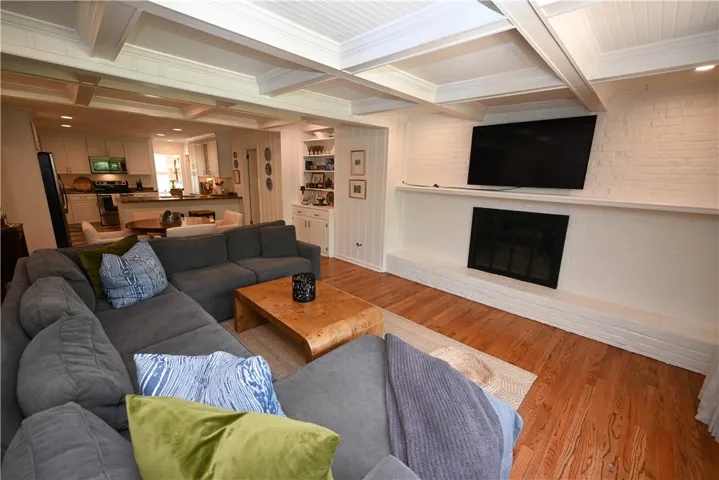 Warm & inviting great room boasts wood-burning fireplace & coffered ceiling.