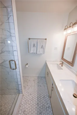 Exquisitely updated primary bath with double sinks & frameless glass shower.