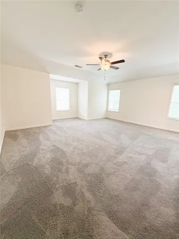 This spacious Primary Bedroom offers abundant natural light and comfortable carpeting, perfect for relaxation.