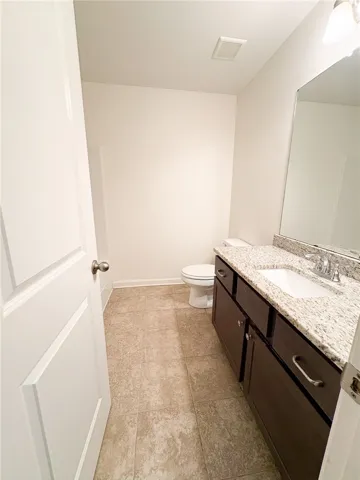 This shared hall bathroom features a contemporary vanity with a spacious granite counter.