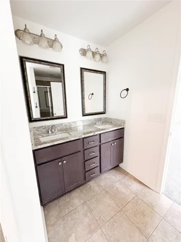 This primary en suite bathroom features a double vanity and sleek countertops, providing ample space for daily routines.