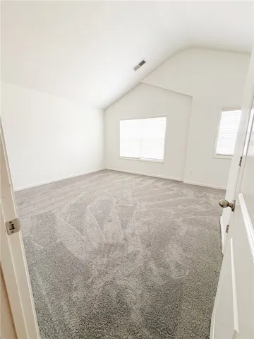 Bedroom 5 features vaulted ceilings, ample natural light, and comfortable carpeting.
