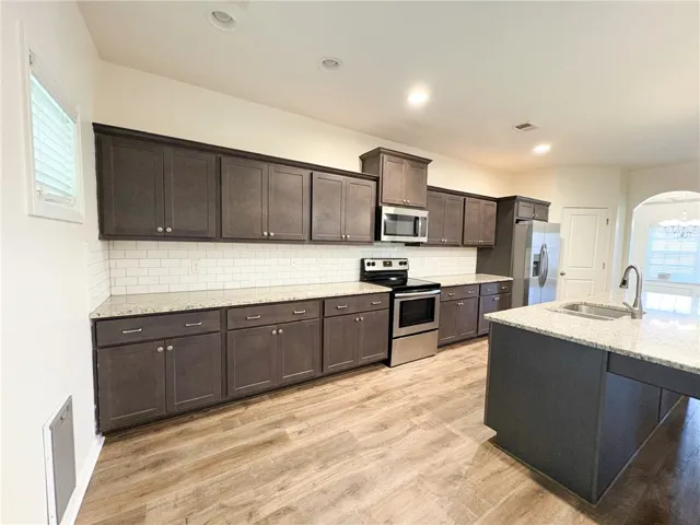 This modern kitchen features a spacious island and stainless steel appliances, creating a functional cooking space.