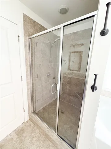 This primary bathroom features a sleek glass shower and durable tile flooring.