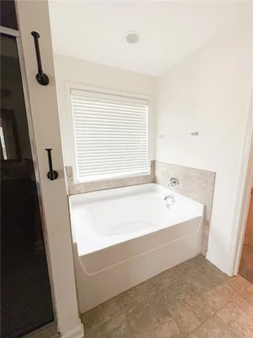 Relax and unwind in this inviting primary bathroom featuring a deep soaking tub.