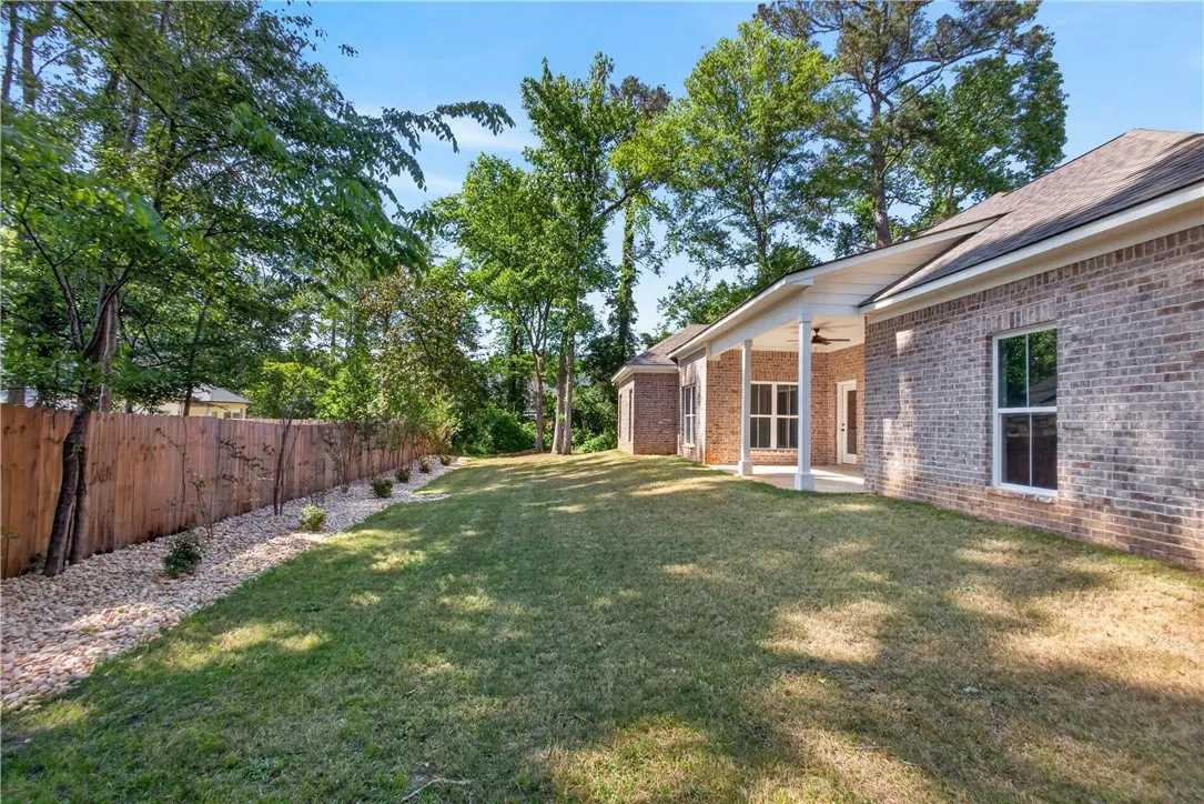 This spacious backyard features a privacy fence, lush lawn, and an inviting covered patio, perfect for outdoor living.