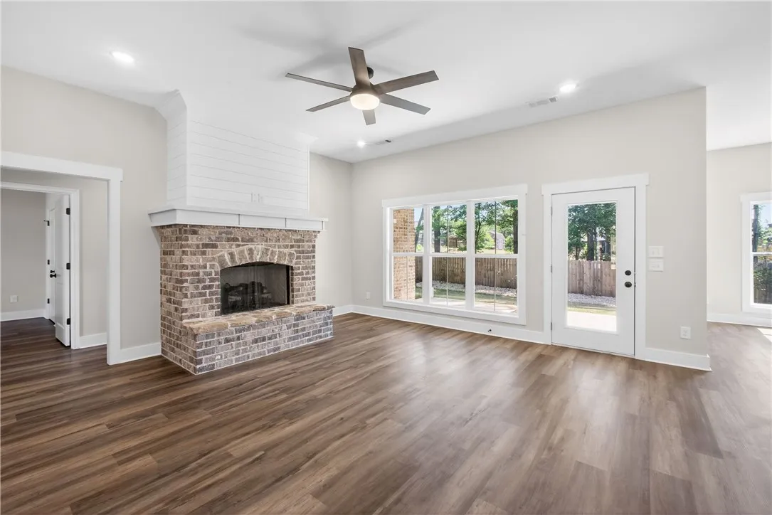 This bright living room features rich wood flooring, a stately brick fireplace, and ample natural light.