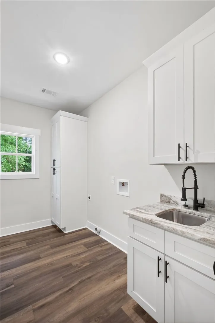 This bright laundry room features ample storage and a practical utility sink.