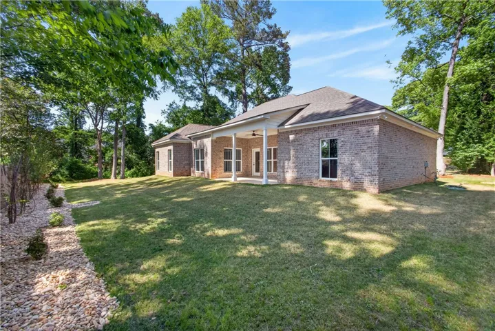 This residence features a covered patio perfect for outdoor living, surrounded by mature trees.