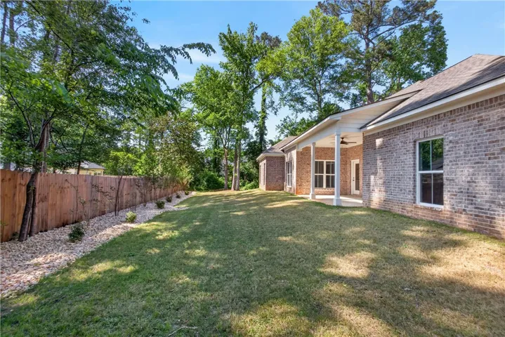 This spacious backyard features a privacy fence, lush lawn, and an inviting covered patio, perfect for outdoor living.