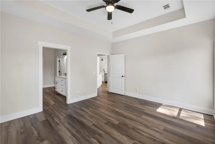 This primary bedroom features elegant flooring and a ceiling fan, offering a comfortable and stylish retreat.