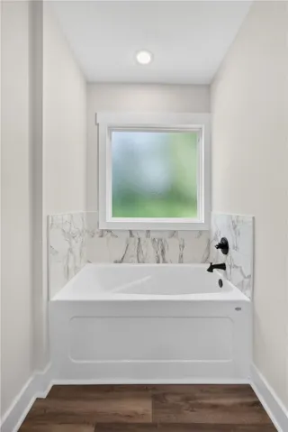 This bright bathroom features a classic bathtub with modern fixtures and a window for natural light.