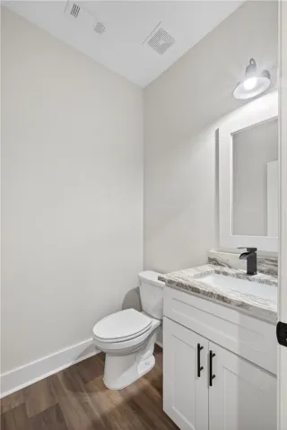 This clean and bright powder room features a modern vanity with elegant countertops.