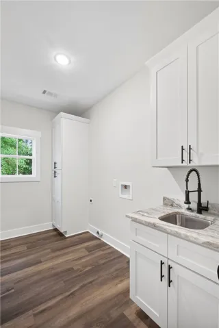 This bright laundry room features ample storage and a practical utility sink.