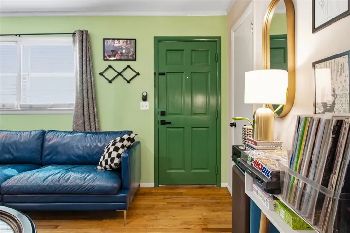 This inviting entryway showcases polished hardwood flooring and a vibrant green door, creating a welcoming first impression.