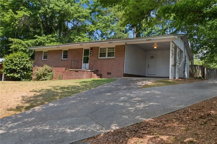 This classic brick residence features an attached carport and a lengthy concrete driveway.