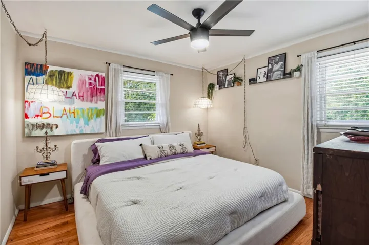This cozy bedroom offers a tranquil retreat with warm wood floors and ample natural light.