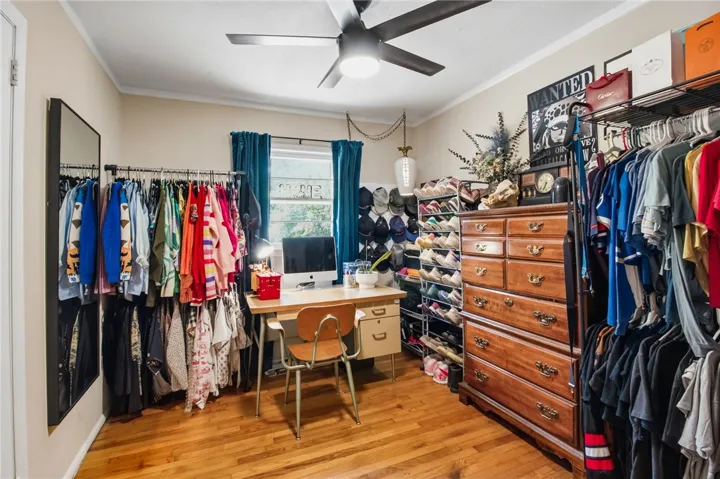 This cozy bedroom features hardwood floors and a ceiling fan, perfect for comfortable living.