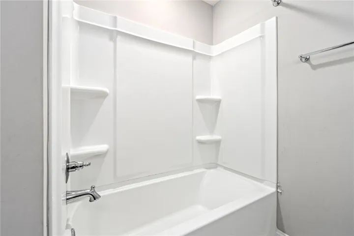 A pristine white bathtub and shower surround offer a clean and inviting bathing space.