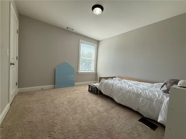 This cozy bedroom offers a tranquil retreat with soft carpet and a bright window.