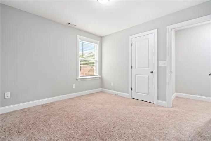 A well-lit bedroom with fresh carpet offers a blank canvas for personalization.