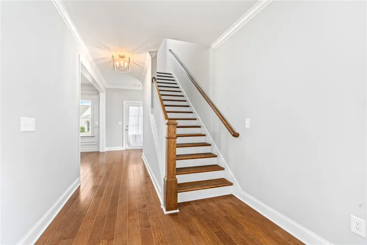 A graceful staircase with rich wooden treads complements the warm hardwood flooring in this inviting entryway.