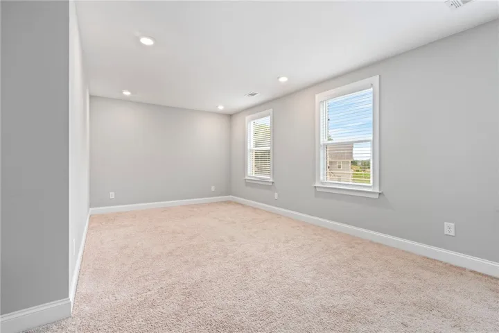 Recessed lighting illuminates this inviting bedroom, offering a comfortable and adaptable living space.