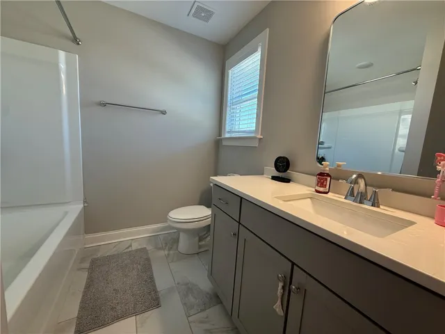 This clean bathroom features sleek fixtures and a spacious vanity, offering both style and functionality.
