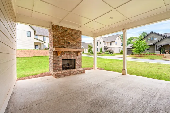 A spacious covered patio features a brick fireplace, offering a cozy outdoor living area.