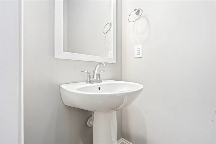 A sleek pedestal sink and framed mirror create a crisp, functional bathroom space.