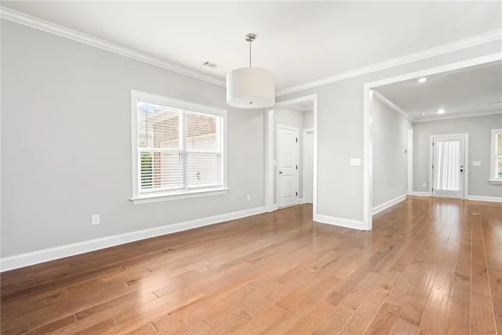 Natural hardwood flooring flows throughout this open-concept room, illuminated by a large window and modern lighting.