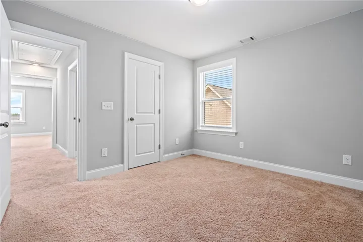 A spacious room featuring comfortable carpeting and a window offering a glimpse of the neighborhood.