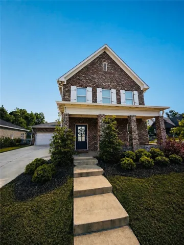 This classic brick residence features an inviting front porch and a neatly landscaped yard.