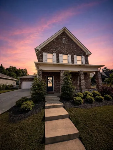 This classic brick home offers an inviting facade, featuring a welcoming porch and a manicured landscape.