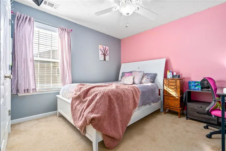 This cozy bedroom features a bright window and soft carpeting, creating a warm and inviting atmosphere.