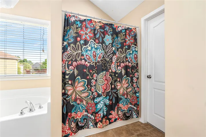 This bathroom offers a relaxing soaking tub and practical tiled flooring for everyday comfort.