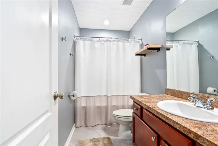 This bathroom features a functional vanity with a sleek countertop and a clean, inviting shower area.