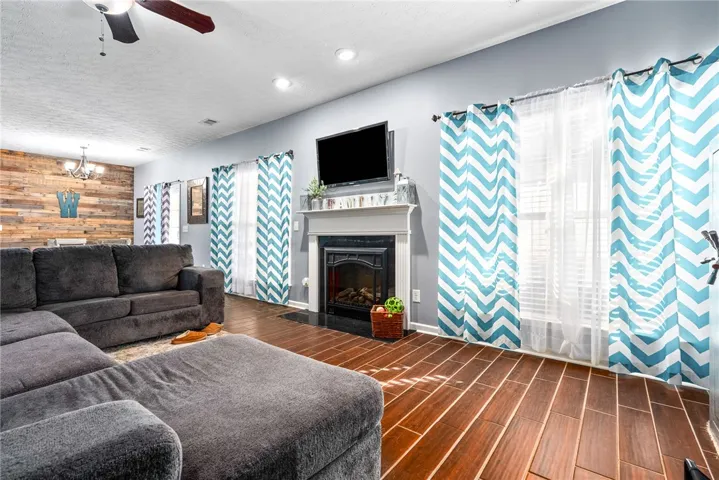 This inviting living space features warm flooring, a fireplace, and bright natural light.